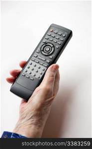 An elderly hand with a TV DVD remote control