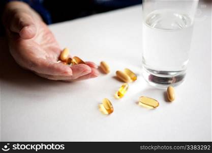 An elderly hand with a variety of large pills