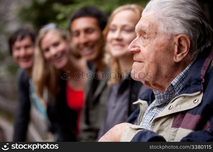 An elderly man telling stories to a group of young people in the forest