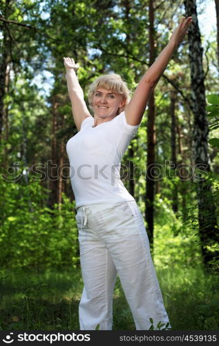 An elderly woman practices yoga in nature. The symbol of healthy lifestyle