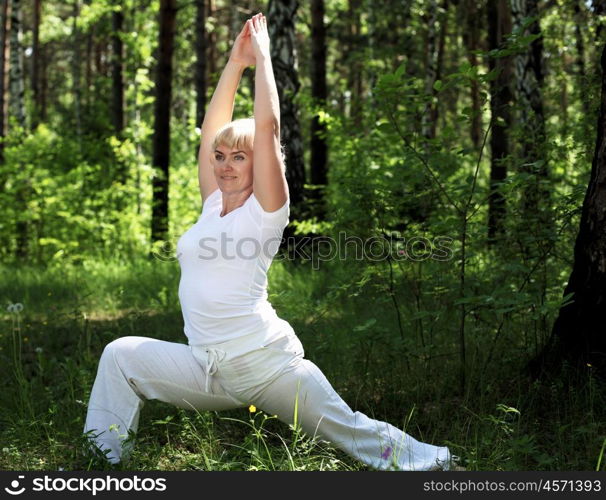 An elderly woman practices yoga in nature. The symbol of healthy lifestyle