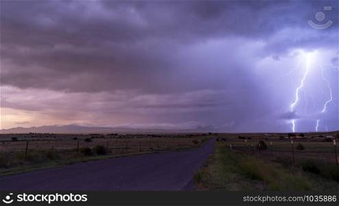 An electrical storm passes over farm land in Arizona Territory producing powerful lightning bolts