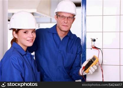 an electrician and his female colleague checking an electrical outlet