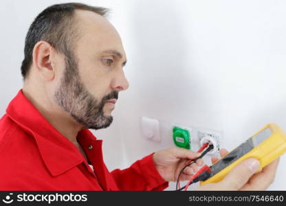 an electrician checking socket voltage