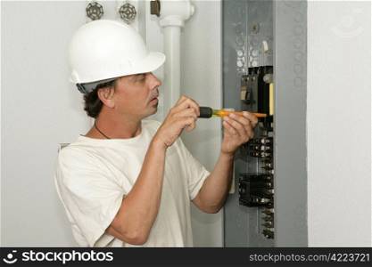 An electrician installing a breaker in an electric panel. Model is an actual electrician and all work is being performed according to industry codes and safety practices.