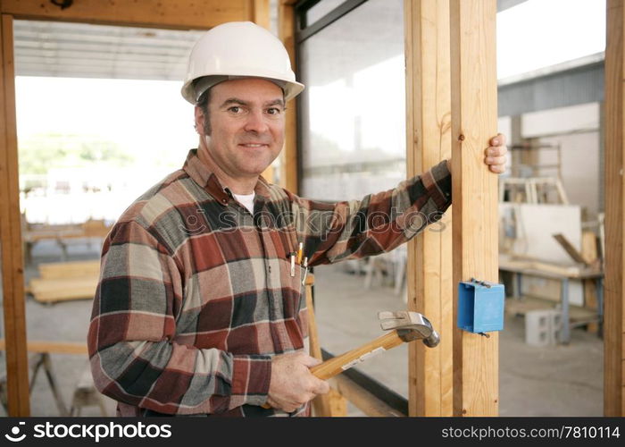 An electrician on a construction site installing an electrical box. Model is a licensed master electrician. Work depicted is accurate and in compliance with codes and safety standards.