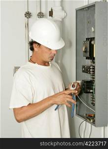 An electrician trimming wire as he hooks up an electrical panel. Model is an actual electrician and all work is being performed in accordance with industry code and safety standards.