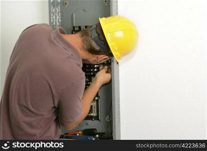 An electrician working on an electrical panel, connecting a wire to a breaker. Model is an actual electrician and all work performed is in accordance with industry standard safety and code regulations.
