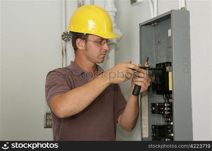 An electrician working on an industrial breaker panel. Model is an actual electrician performing all work to industry codes and safety standards.