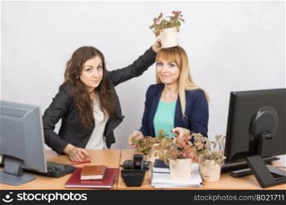 An employee of the office puts on a head-grower colleagues with a flower pot