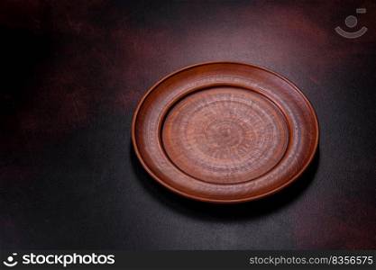 An empty brown ceramic plate on a dark concrete brown background. Preparing the Dinner Table. An empty brown ceramic plate on a dark concrete brown background
