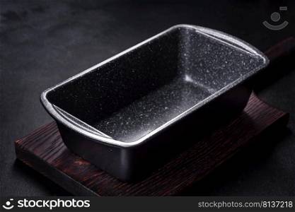 An empty ceramic grey baking dish on a dark concrete background. Preparation for baking tasty cupcake. An empty ceramic grey baking dish on a dark concrete background