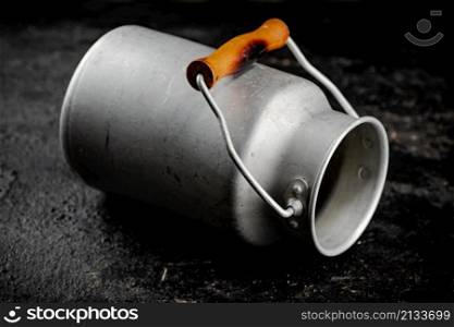 An empty milk can on the table. On a black background. High quality photo. An empty milk can on the table.