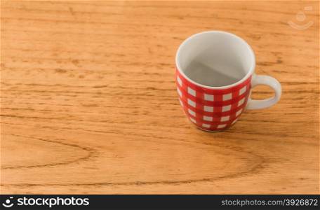 an empty red and white striped coffee cup over a wooden table