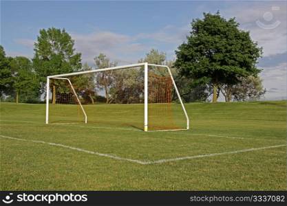 An empty soccer goal with trees in the background.. Empty Football Net