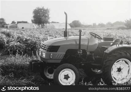 An empty tractor stands on a farmer&rsquo;s field. Black and white. Farm machinery and equipment. Farming industry