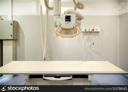 An empty x-ray room with an x-ray machine and table