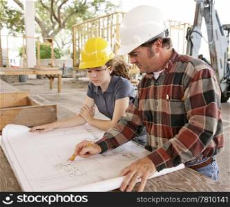 An engineer and a female student going over blueprints on a construction site.