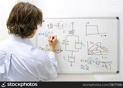 An engineer drawing a complexe physics equation on a whiteboard