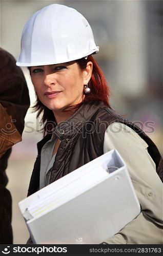 An engineer holding a binder and wearing a safety hat
