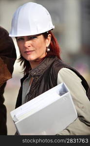 An engineer holding a binder and wearing a safety hat