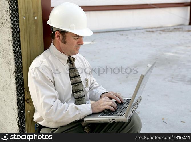 An engineer on a construction site using a laptop computer.