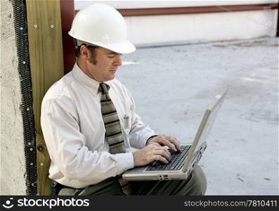 An engineer on a construction site using a laptop computer.