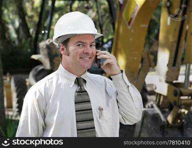 An engineer on the construction site talking on the phone.
