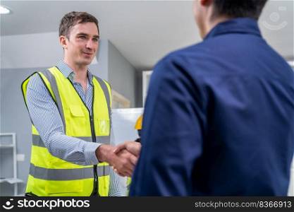 An engineer with a protective vest handshake with an investor in his office. Following a successful meeting, employee and employer form a partnership.. An engineer with a protective vest handshake with an investor in his office
