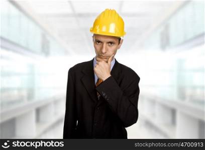 An engineer with yellow hat thinking at the office