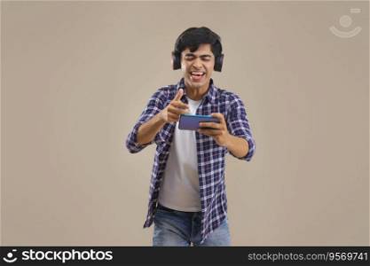 AN ENTHUSIASTIC TEENAGER HAPPILY PLAYING VIDEO GAMES ON MOBILE PHONE