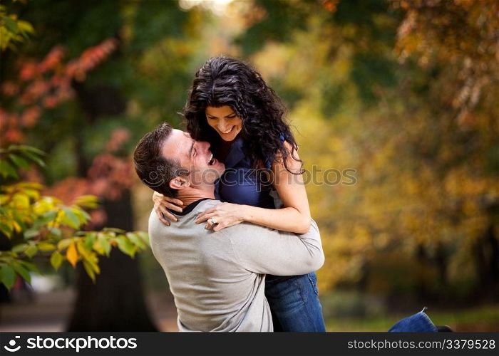 An excited couple giving eachother a big hug in a park