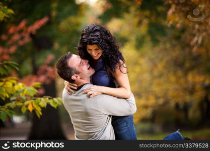 An excited couple giving eachother a big hug in a park