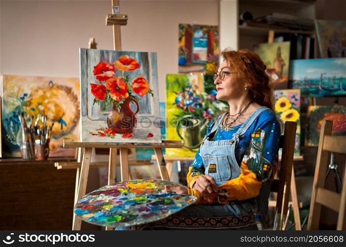 An experienced artist works in her own studio.. Portrait of an artist with a lot of experience on the background of the stu