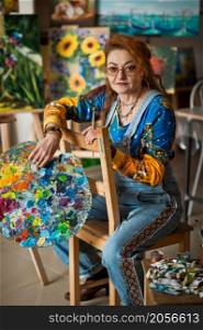 An experienced artist works in her own studio.. Portrait of an artist with a lot of experience on the background of the stu