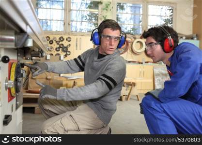 An experienced workman showing an apprentice the ropes