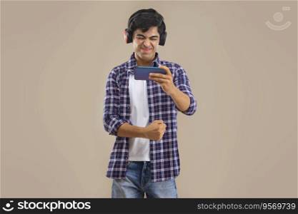 AN EXPRESSIVE TEENAGER HOLDING MOBILE PHONE AND WEARING HEADPHONES