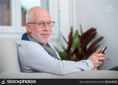 an handsome senior man using phone on the sofa