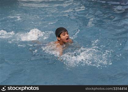 an handsome young indian kid swimming in the pool