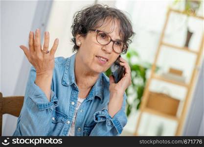 an happy middle age woman with glasses using and talking phone