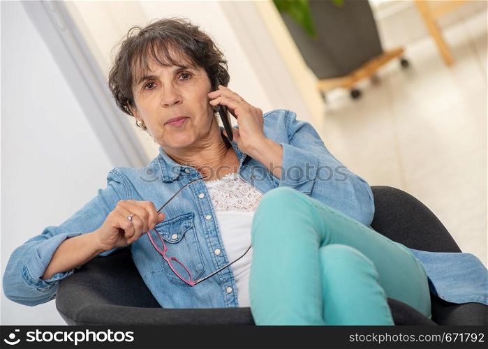 an happy middle age woman with glasses using and talking phone