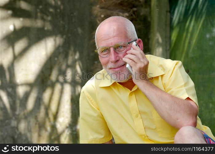 an healthy senior man on the phone outdoor garden