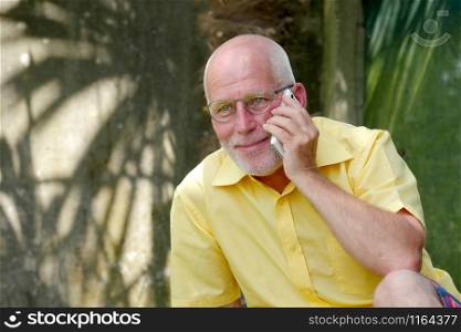 an healthy senior man on the phone outdoor garden