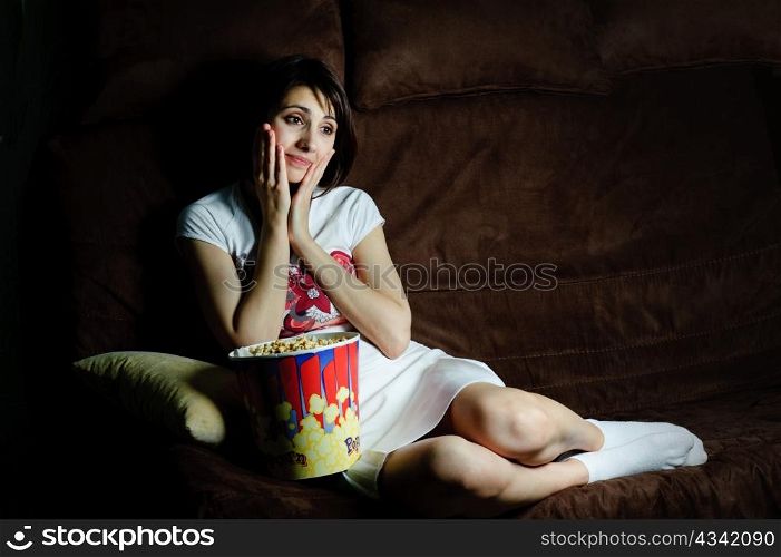 An image of a girl on a sofa watching TV