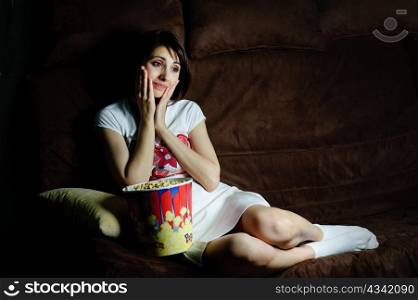 An image of a girl on a sofa watching TV