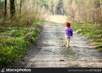 An image of a little girl walking in the forest