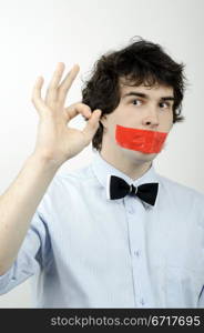 An image of a man with a tape on his mouth showing sign &rsquo;&rsquo;OK&rsquo;&rsquo;