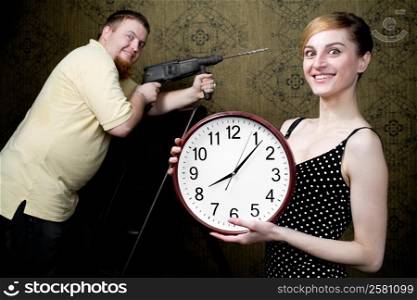 An image of a woman with new clock and a man with drill