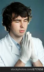 An image of a young doctor in gloves praying