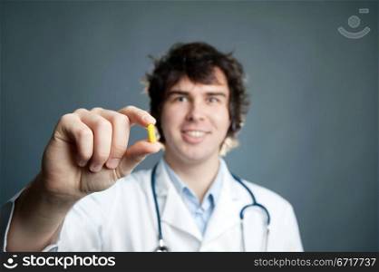 An image of a young doctor with a pill in his hand